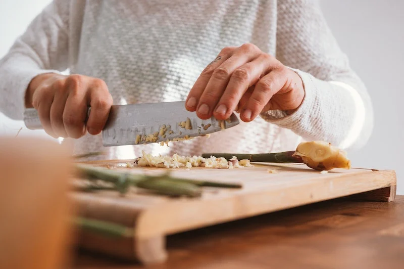 person chopping up garlic on a board