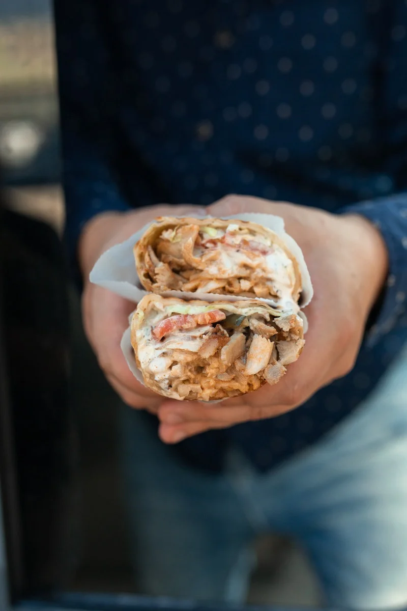 person holding two shawarma wraps