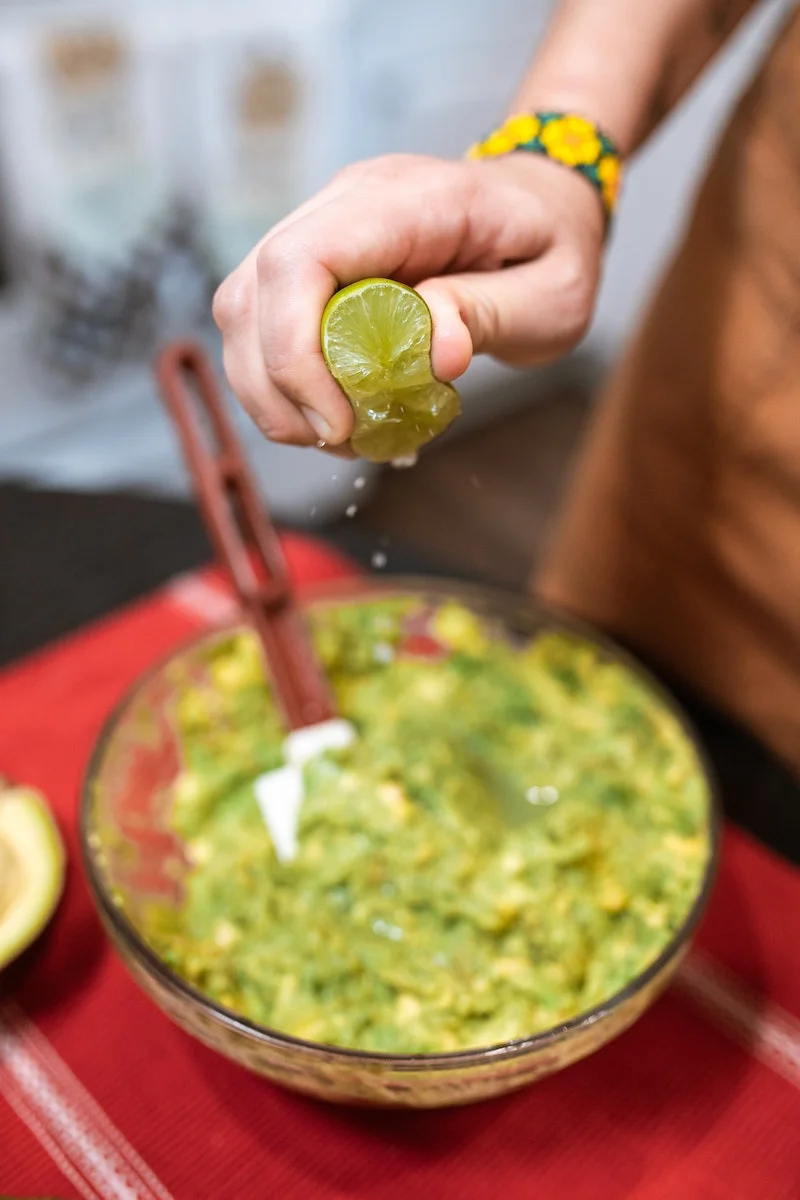 person squeezing lime into guacamole