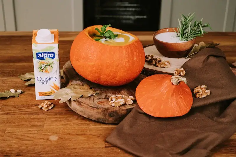 pumpkin soup in a pumpkin garnished with mint leaves