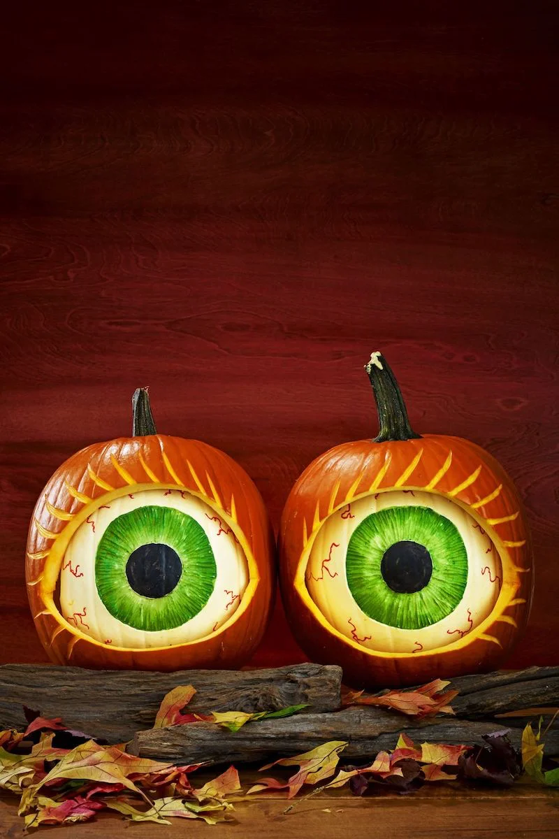 pumpkins carved and painted into two green eyes