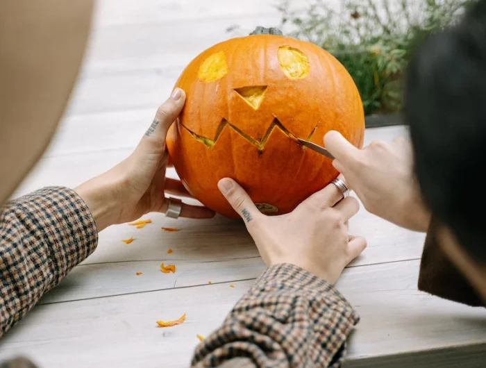two people carving a pumpkin face