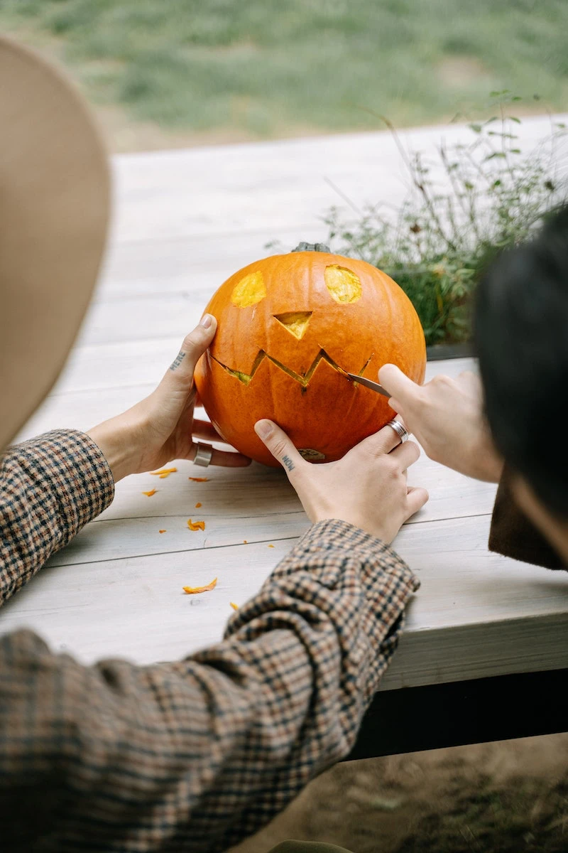 two people carving a pumpkin face