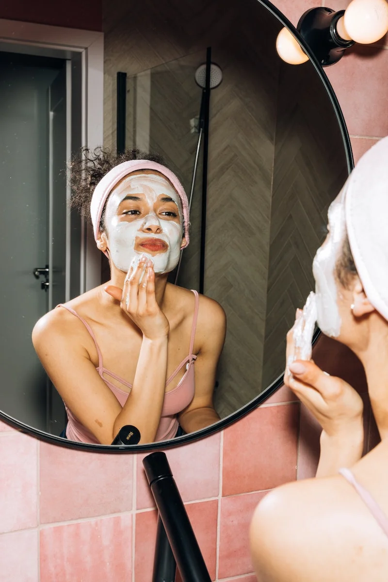 woman applying a green mask on face