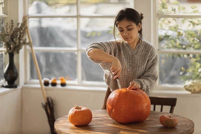 woman carving a pumpkin from the top