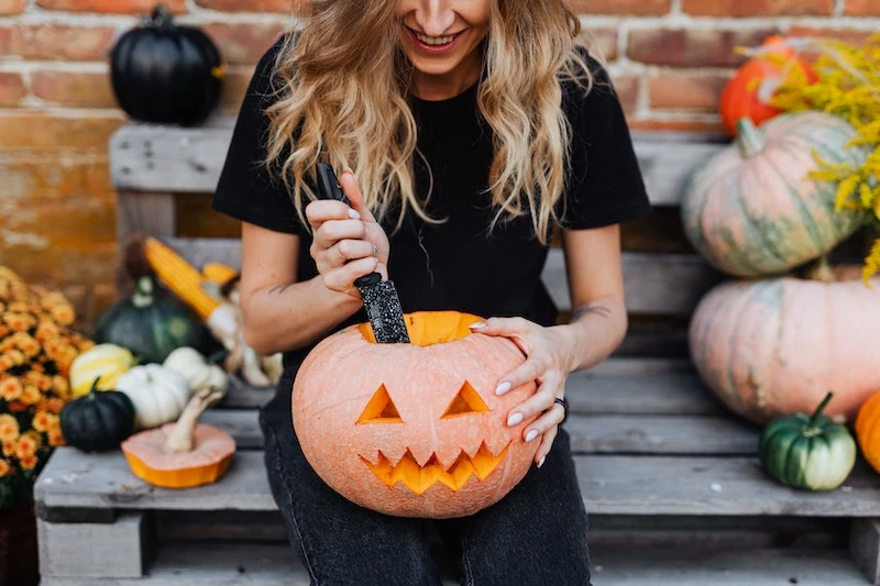 woman carving a pumpkin on her lap