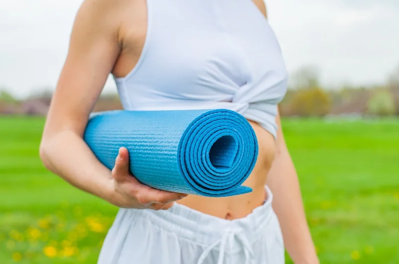woman holding a blue yoga mat