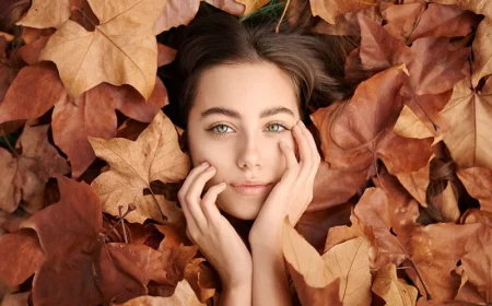 woman laying in between fall leaves