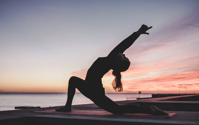 yoga vs pilates woman holding a yoga pose in sunset