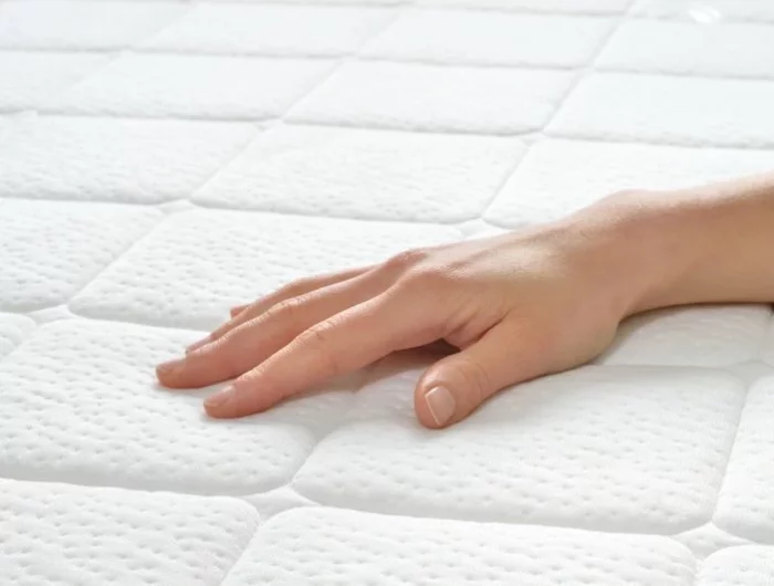 a hand resting on a clean white mattress