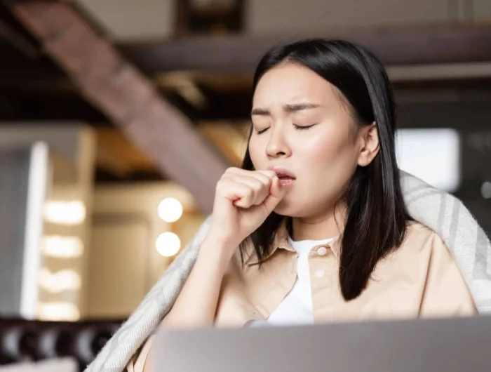 asian woman being ill coughing fist feeling sick home resting with laptop