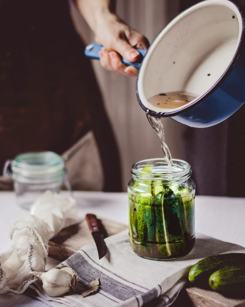 homemade pickles person pouring brine in jar