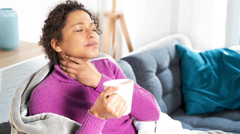 how to get rid of a sore throat woman holding her throat