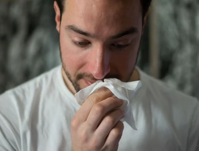 man cleaning his nose with a tissue