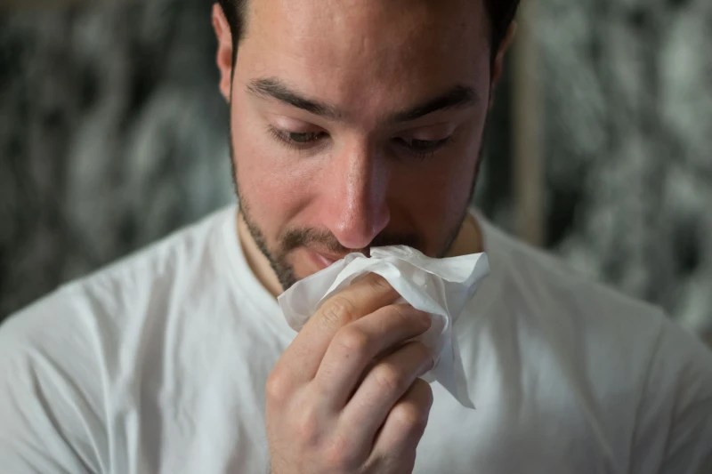 man cleaning his nose with a tissue