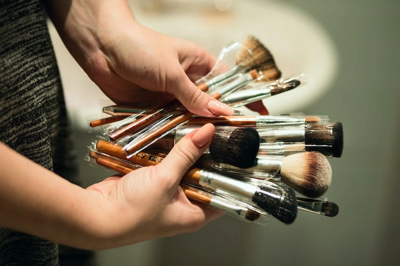 person holding a lot of makeup brushes