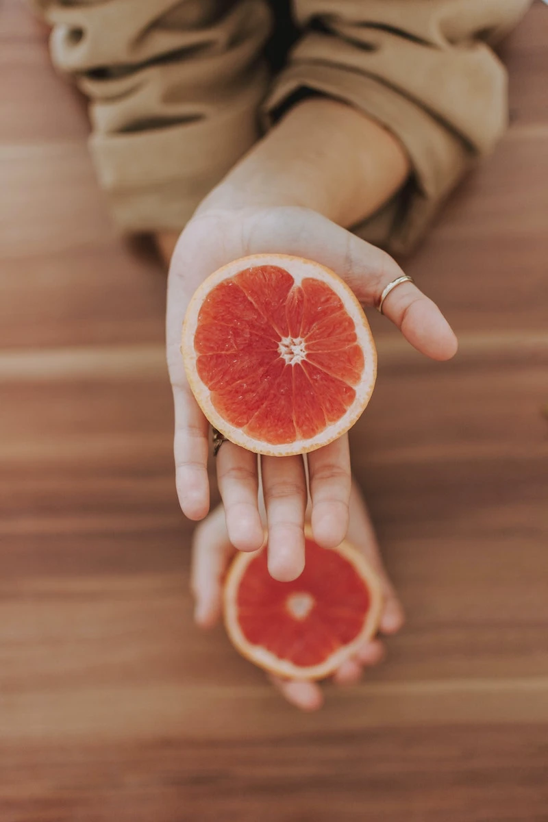 person holding two halves of a grapefruit