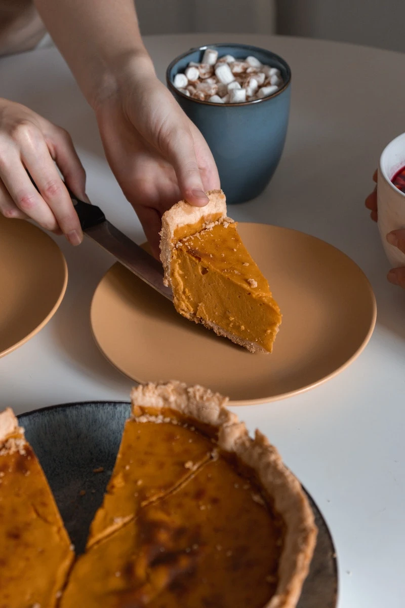 person serving a piece of pumpkin pie