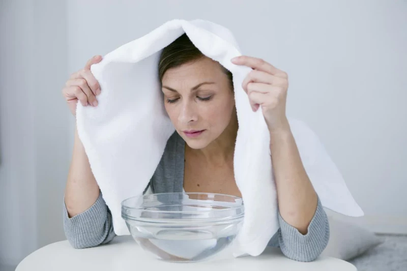 woman hovering over a bowl with towel on head
