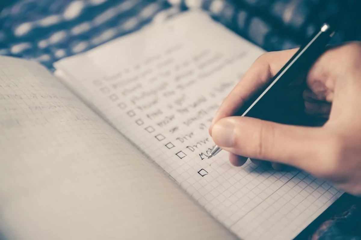 a person writing a checklist into a notebook
