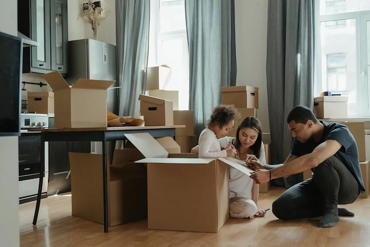 family of three unpacking boxes at new home
