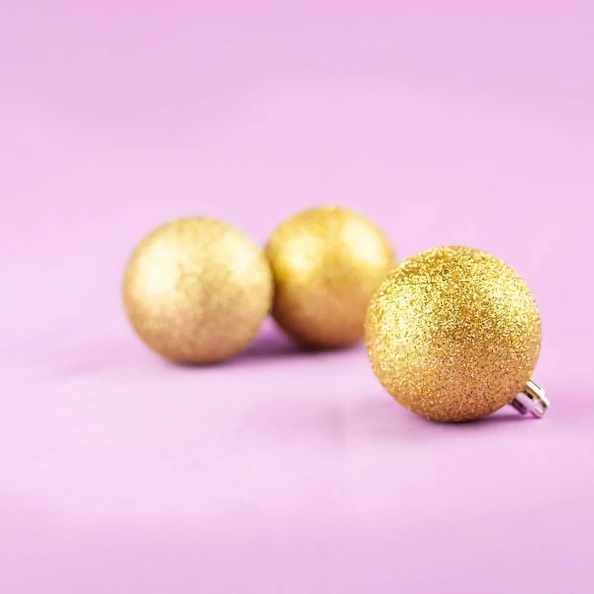 golden glitter ornaments on pink background