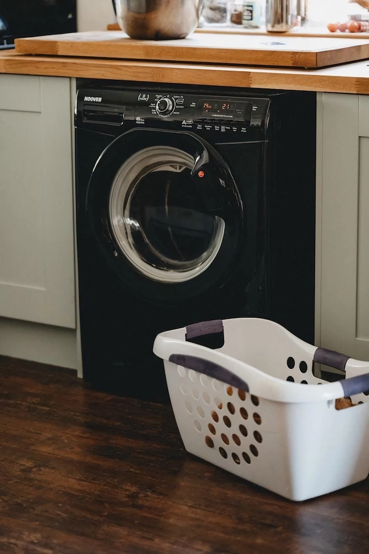 black washing machine with hamper in front of it