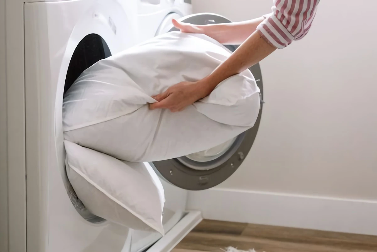 how to wash pillows person putting pillow in dryer