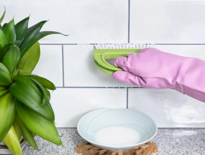 pink gloves and brush cleaning grout