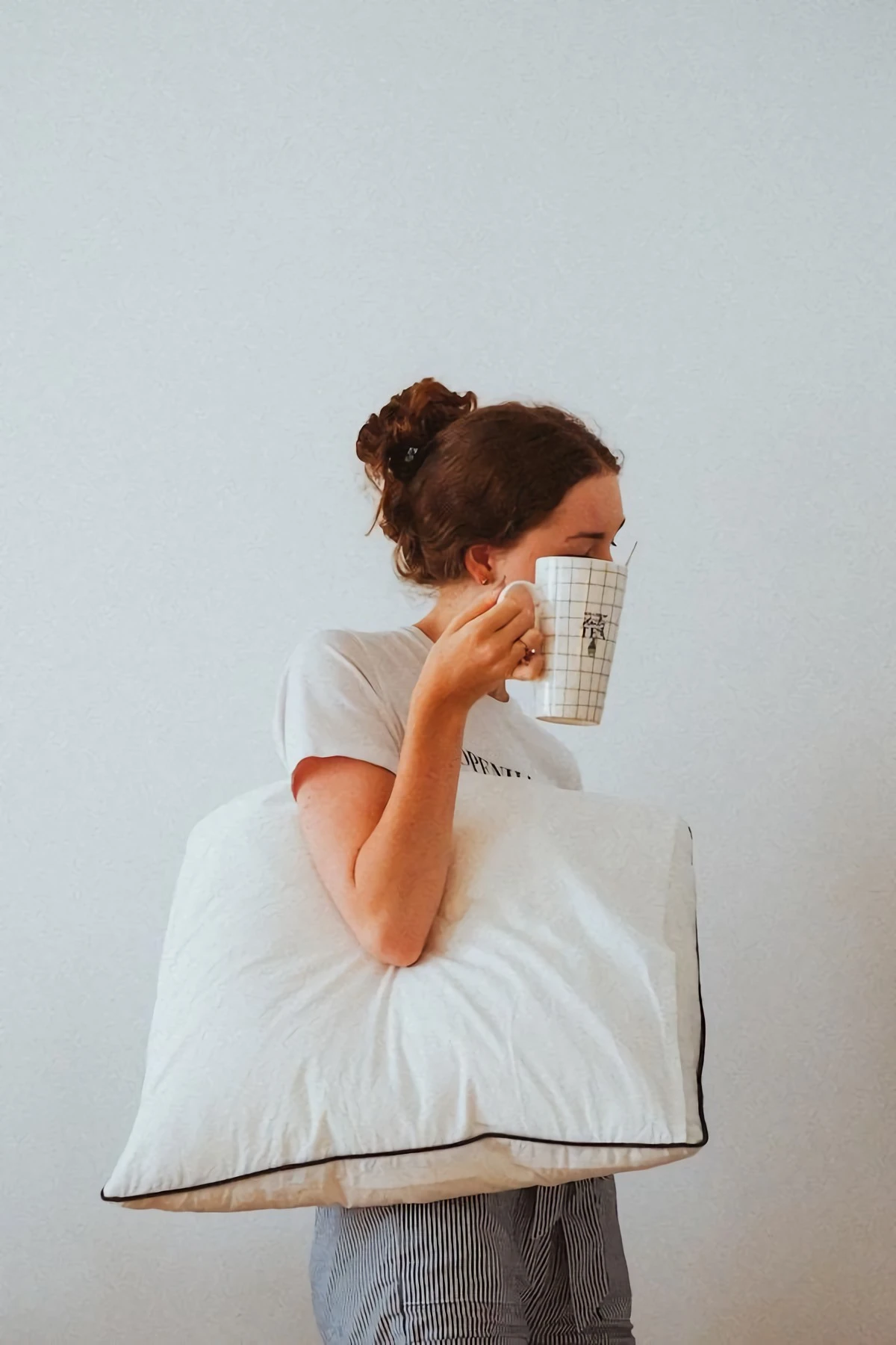 woman holding a pillow and a cup