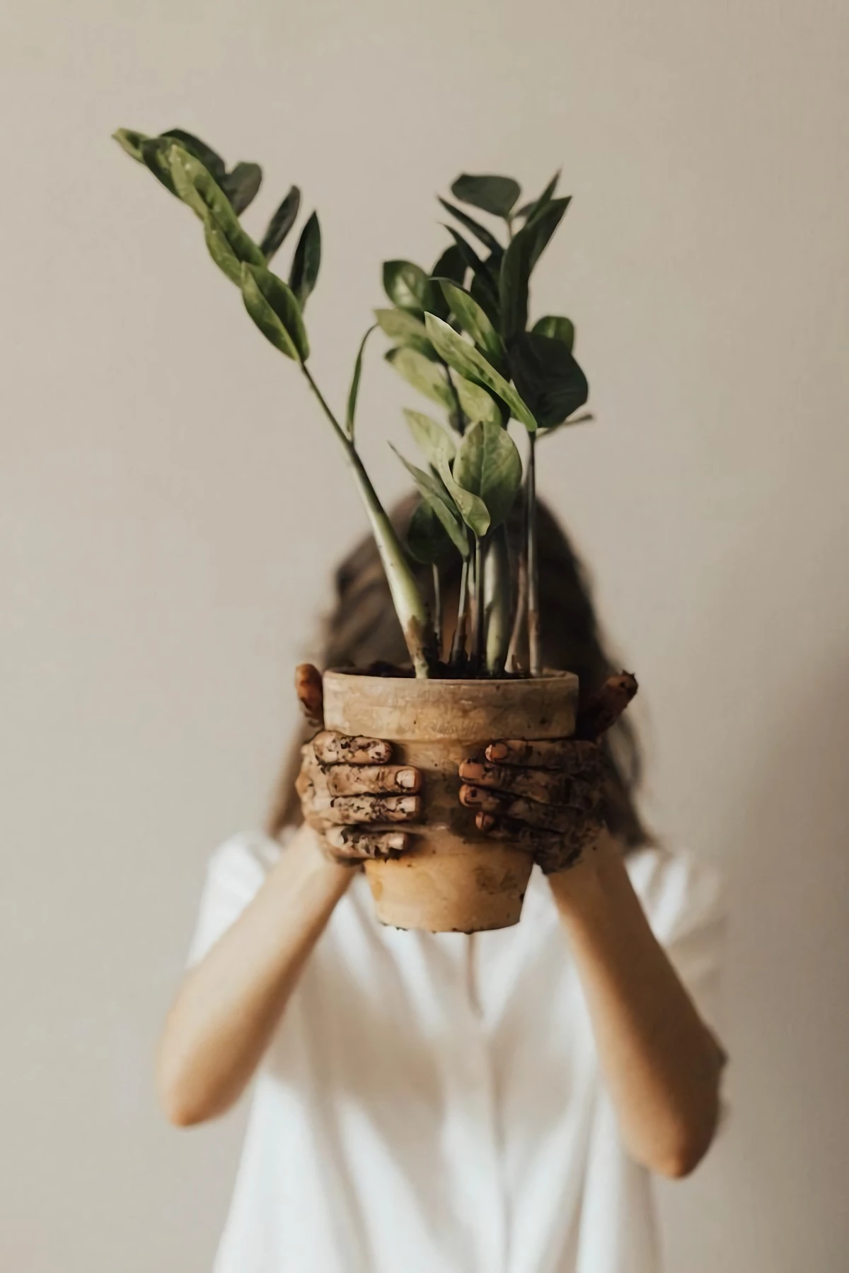woman holding a plant with dirty hands