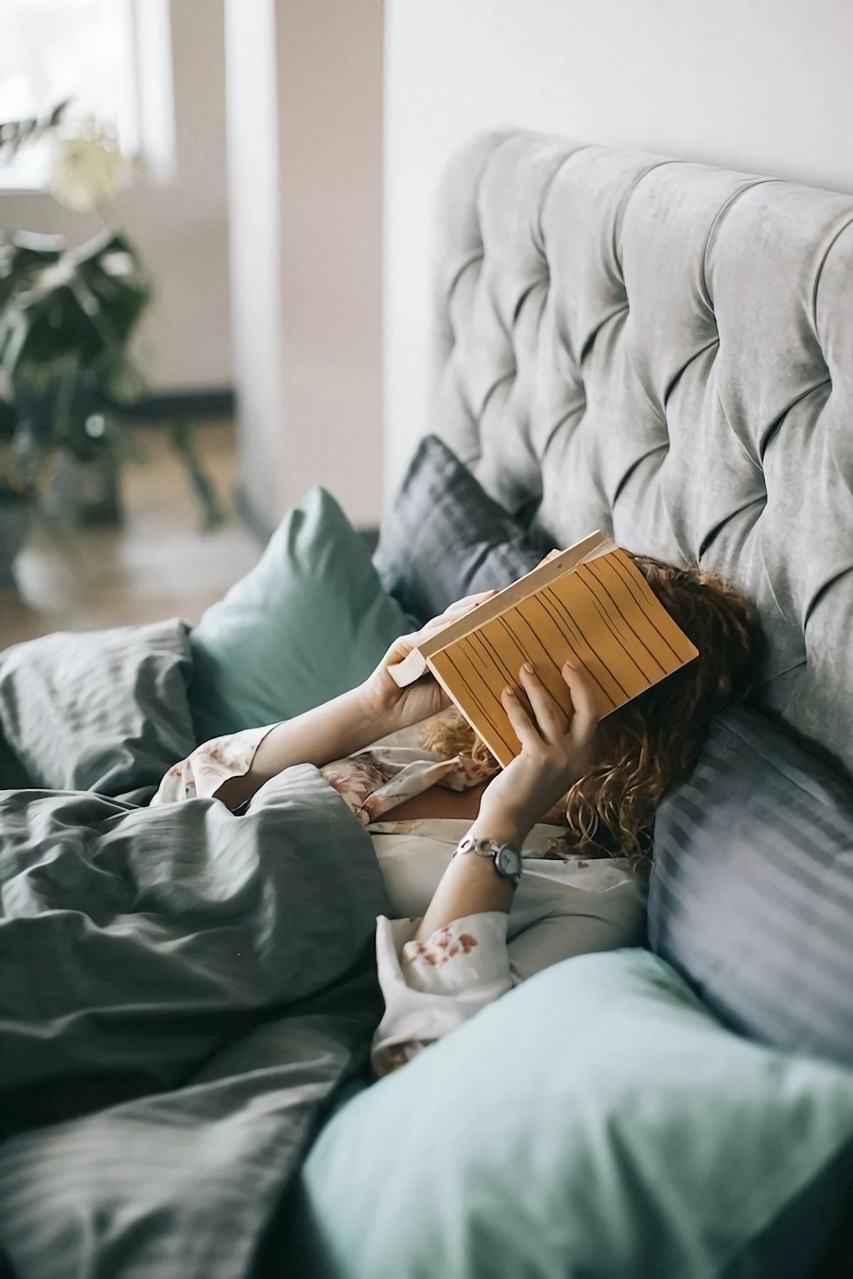woman laying in bed with a book on her head