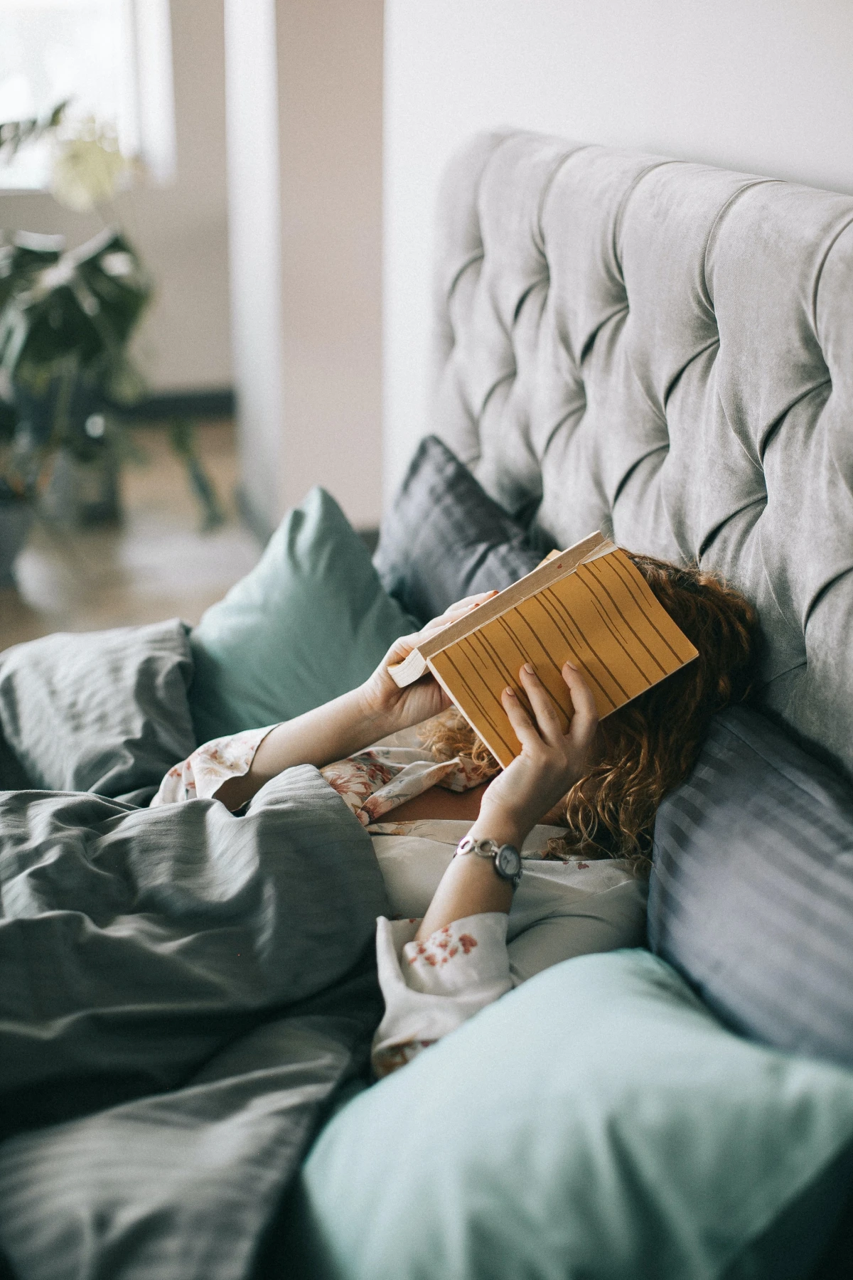 woman laying in her bed with book on0head