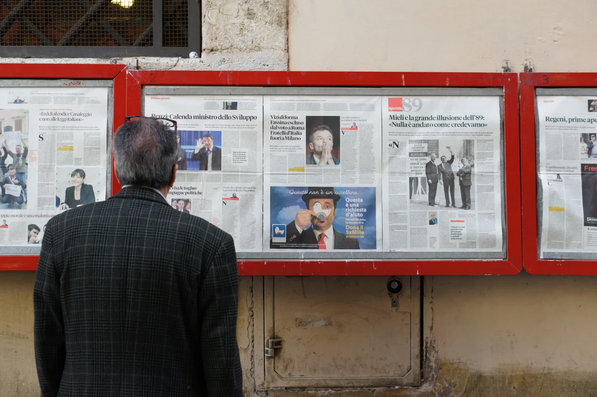 man reading newspapers in stands