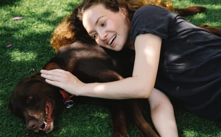 woman and dog laying on grass