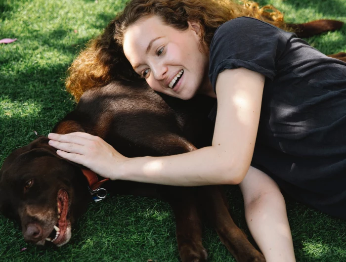 woman and dog laying on grass