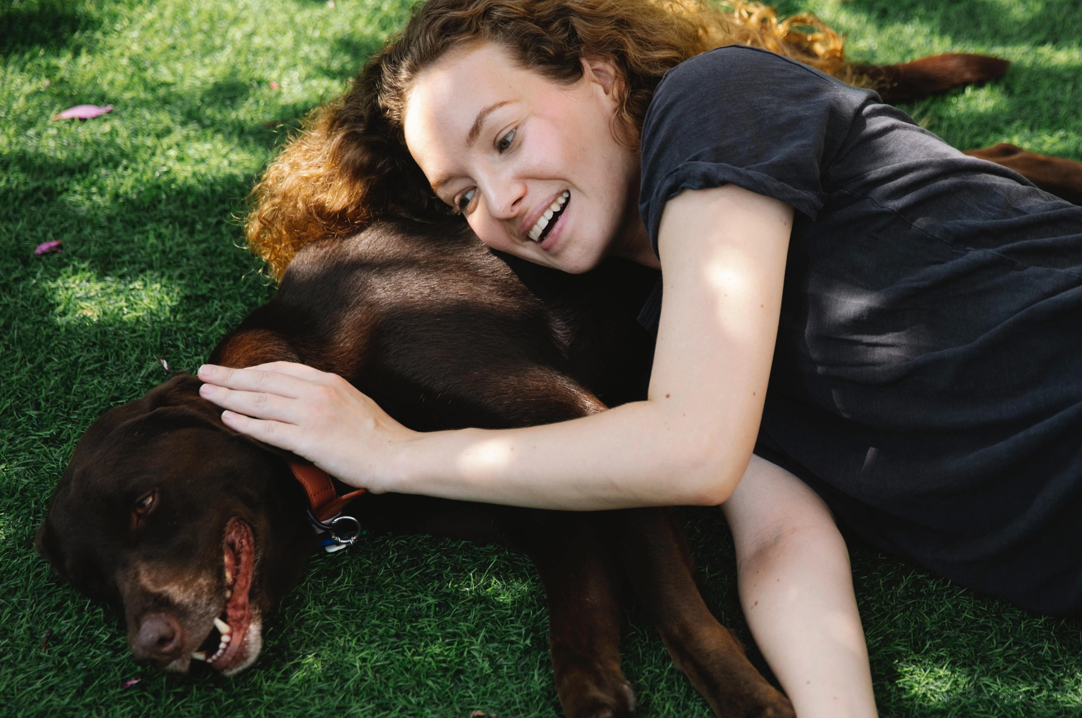 woman and dog laying on grass