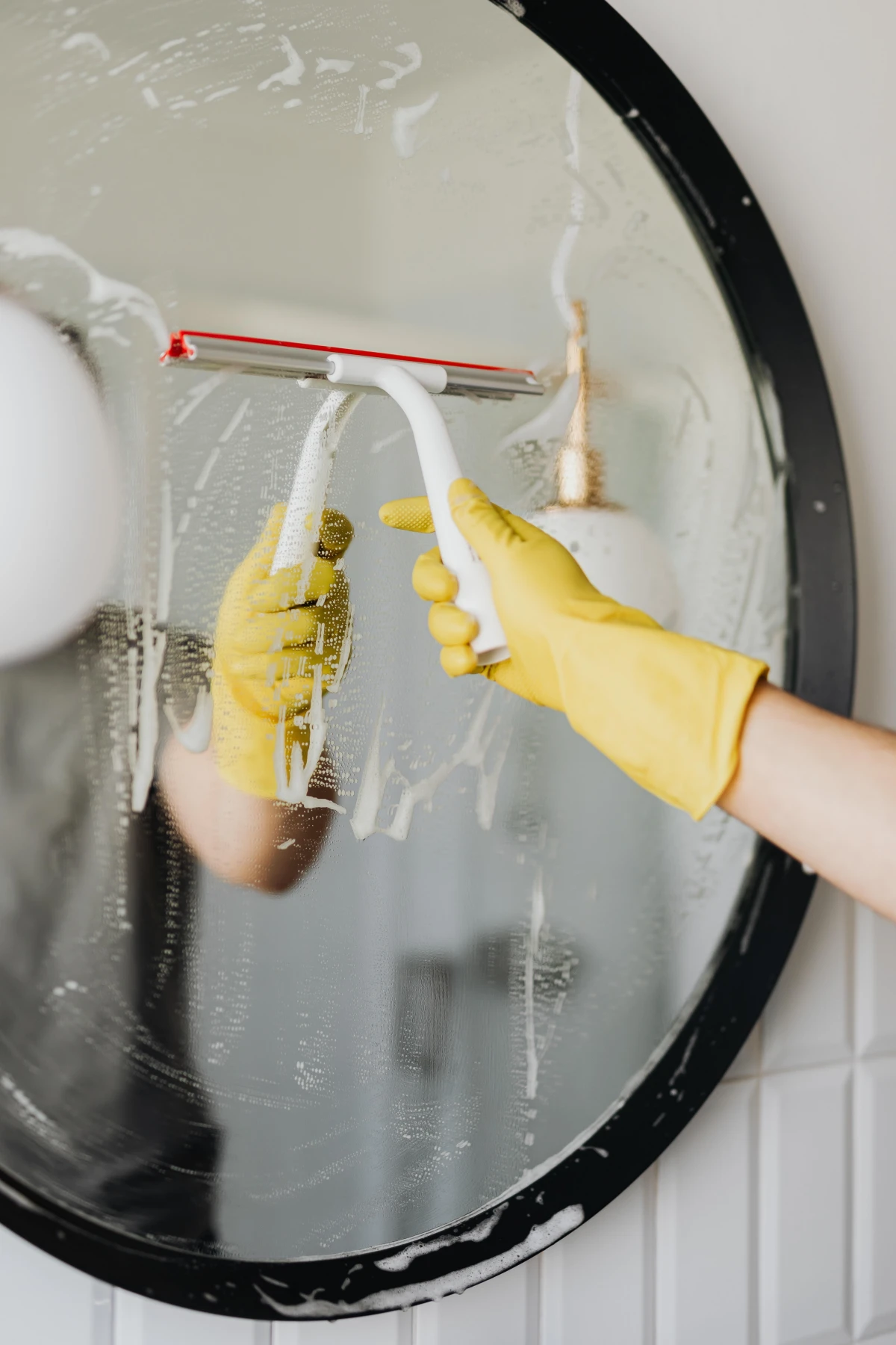 person cleaning mirror with squeegee