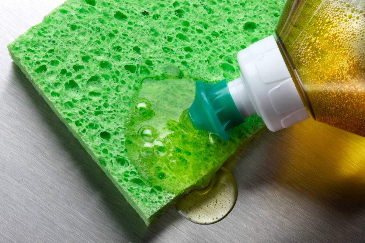 removing tea stains from cups putting dish soap on a green sponge
