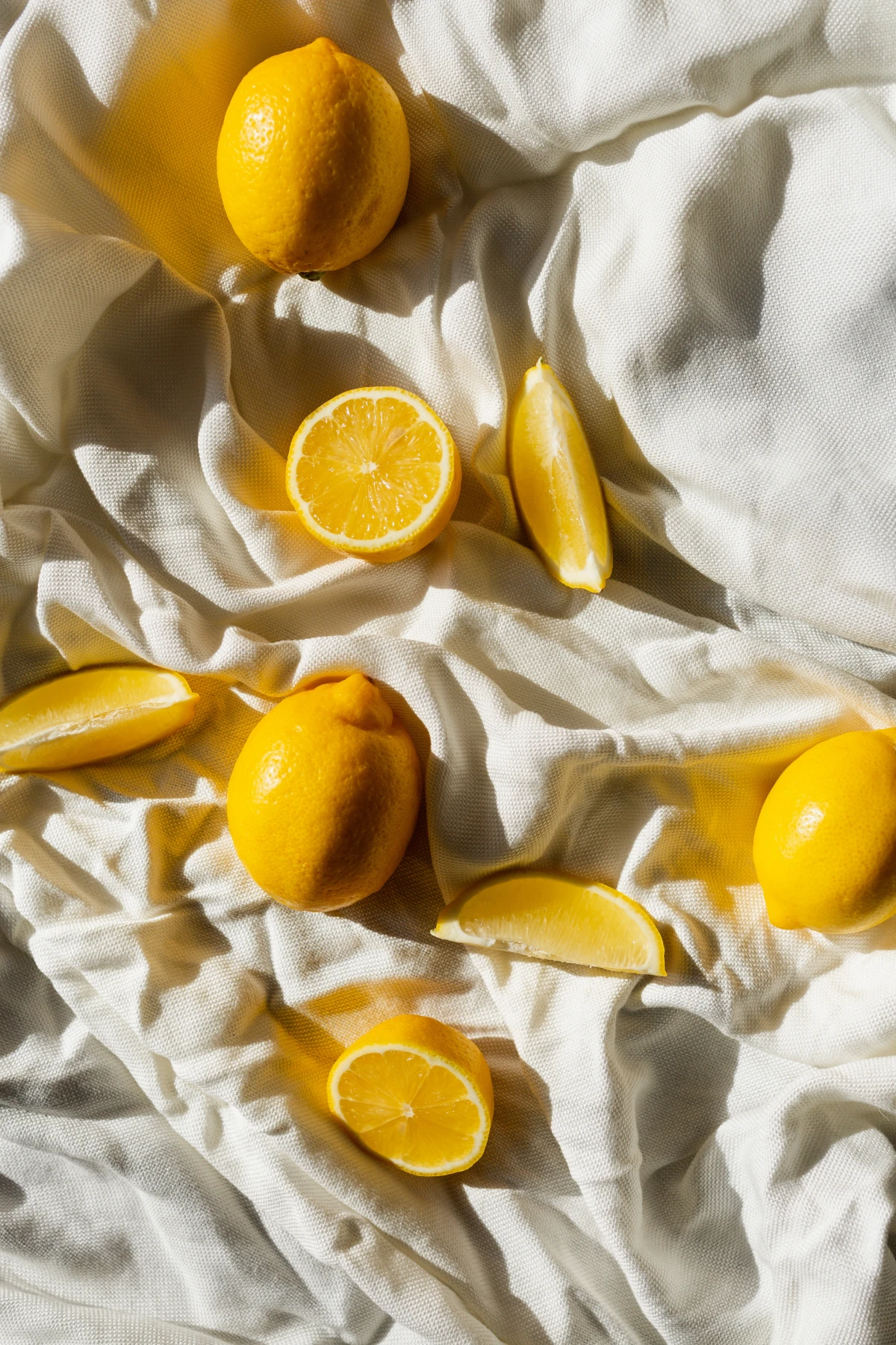cut and whole lemons on white cloth