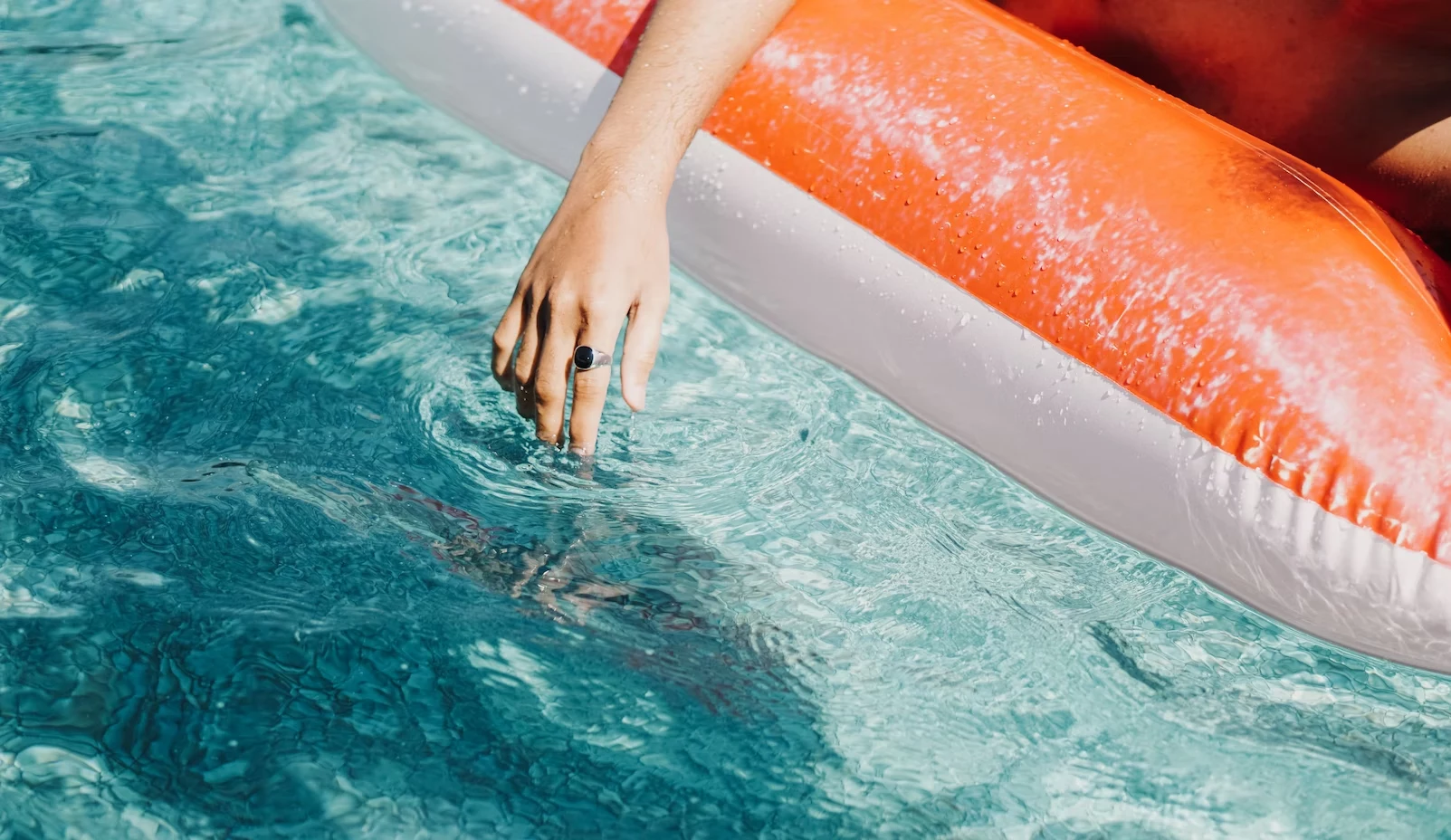 person with hand in swimming pool