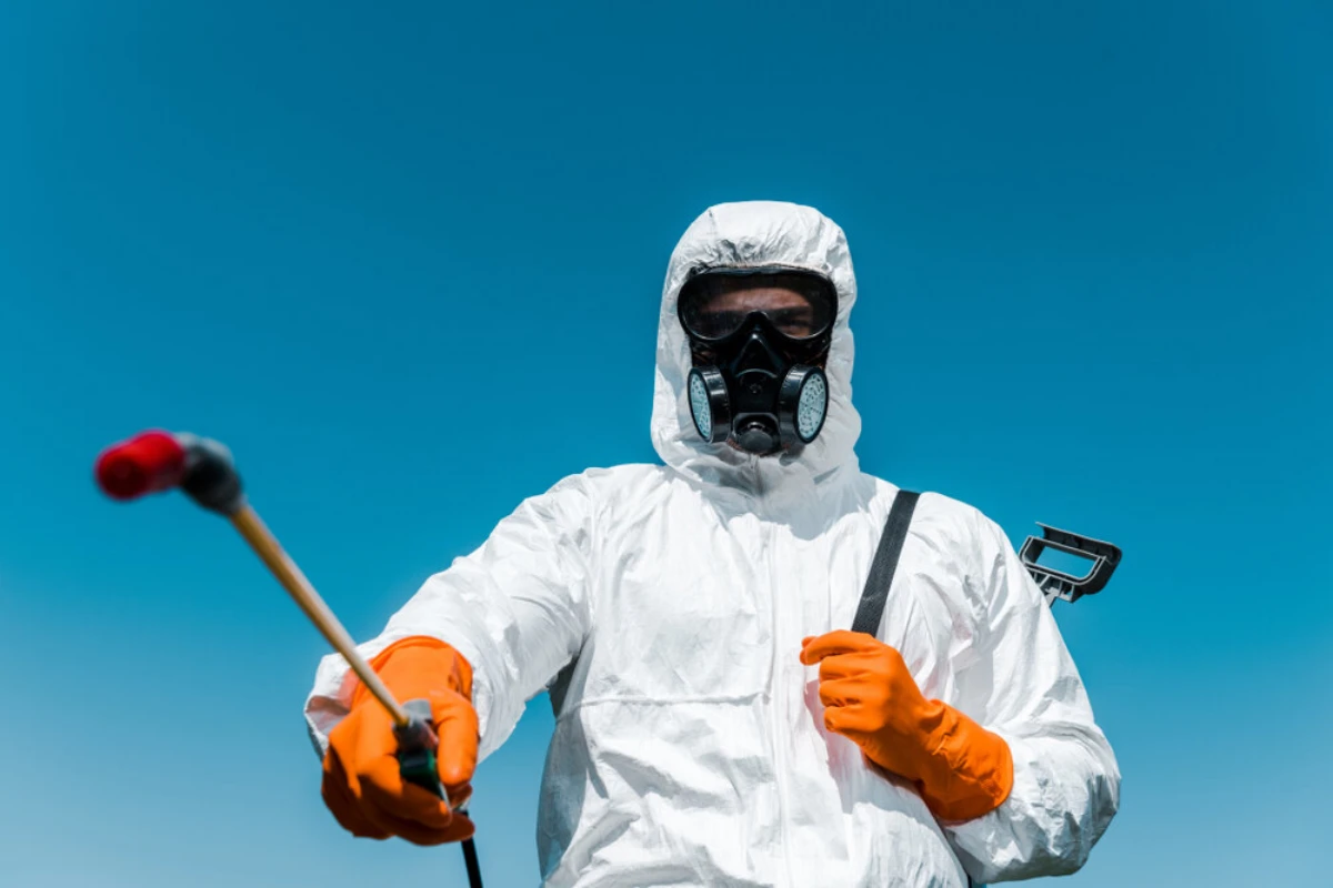 exterminator in white suit with spray