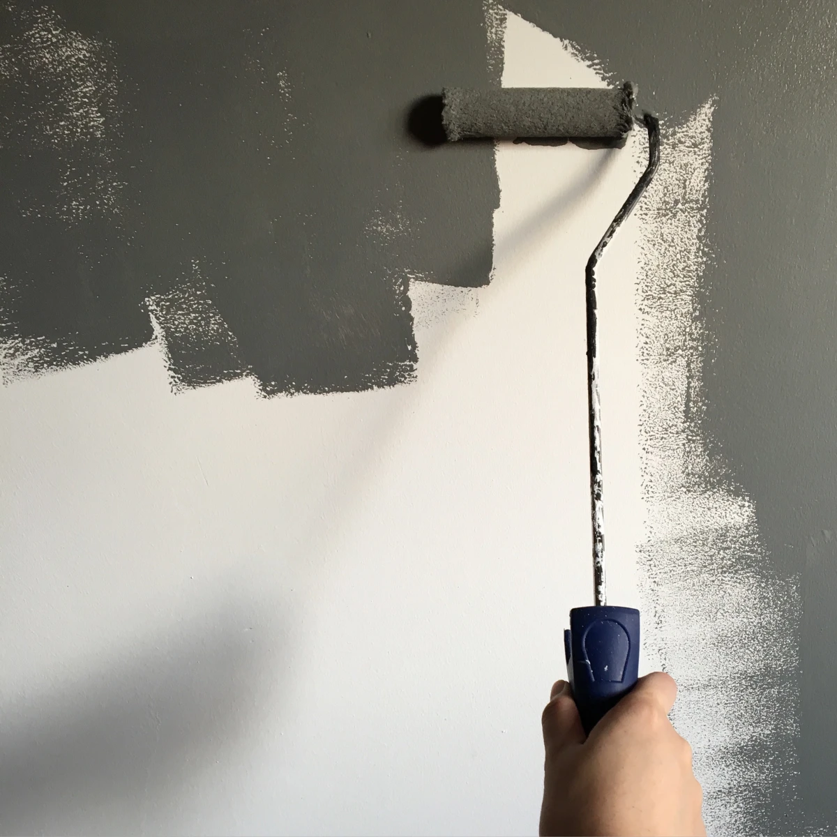 gray paint on roller on wall