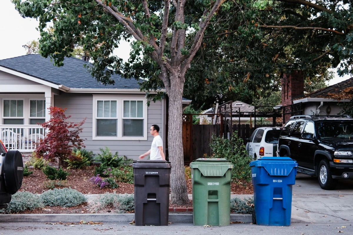 three trash cans in front of house