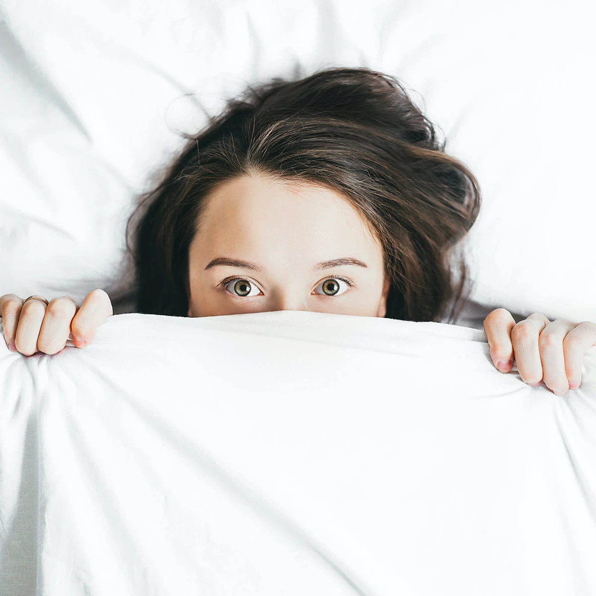 woman eyes wide open under covers