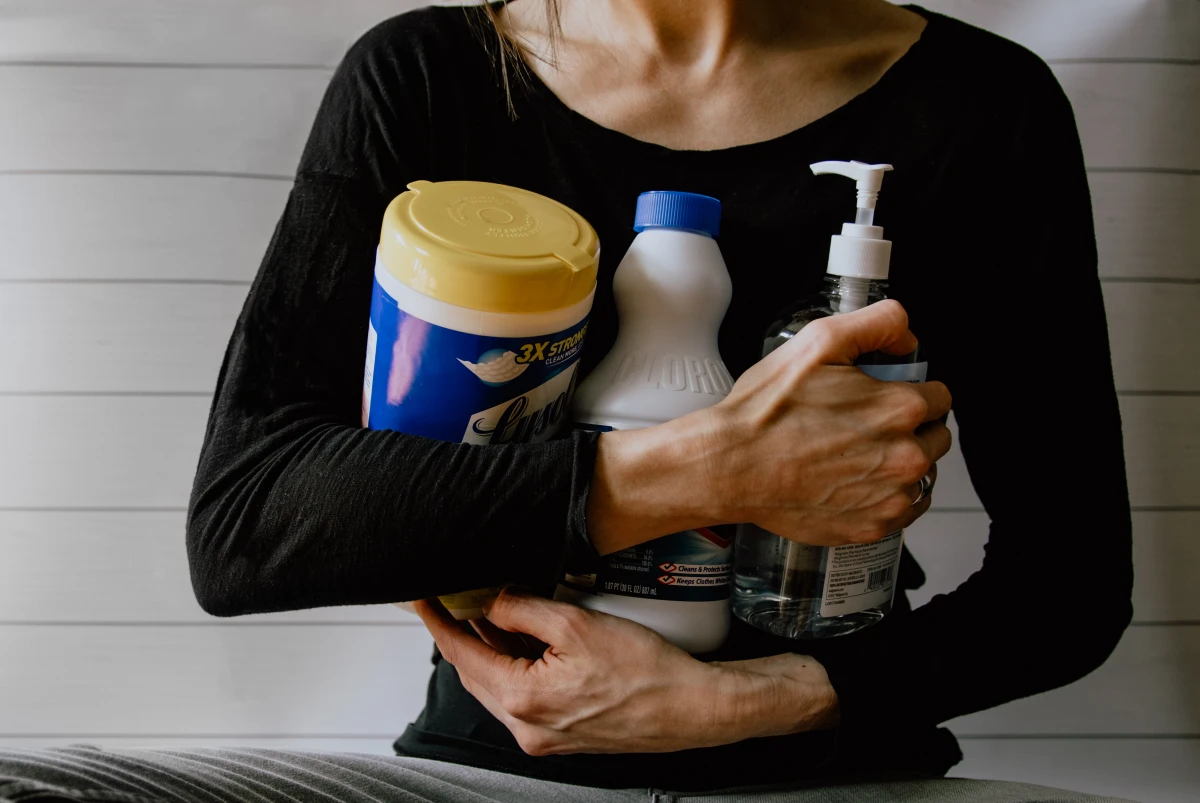 woman holding different cleaning products