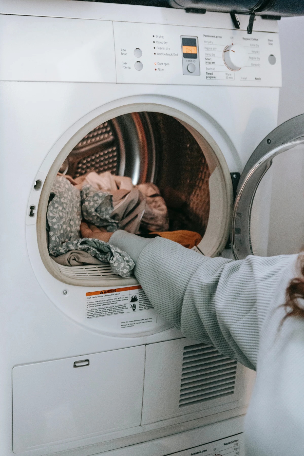 person putting clothes in washing machine
