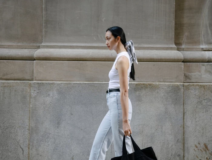 woman walking in jeans tank top and black bag