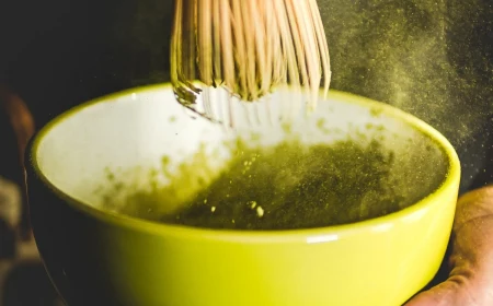 mixing matcha in a bowl with bamboo whisk