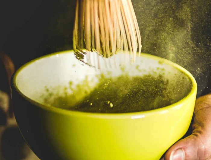 mixing matcha in a bowl with bamboo whisk